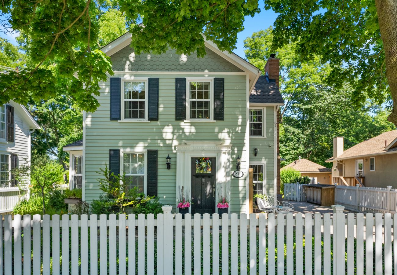 Victorian home with green horizontal siding and white picket fence