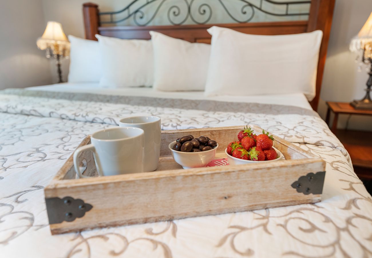 King bed with tray of coffee cups and strawberries