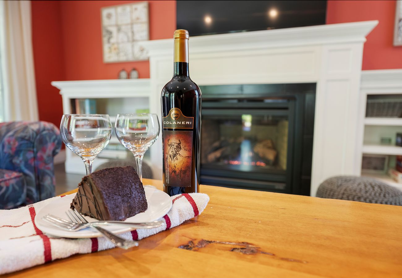 Bottle of wine and chocolate cake with gas fireplace in background