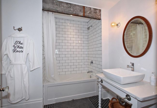 Bathroom with tub-shower combo and bathrobe hanging on the wall
